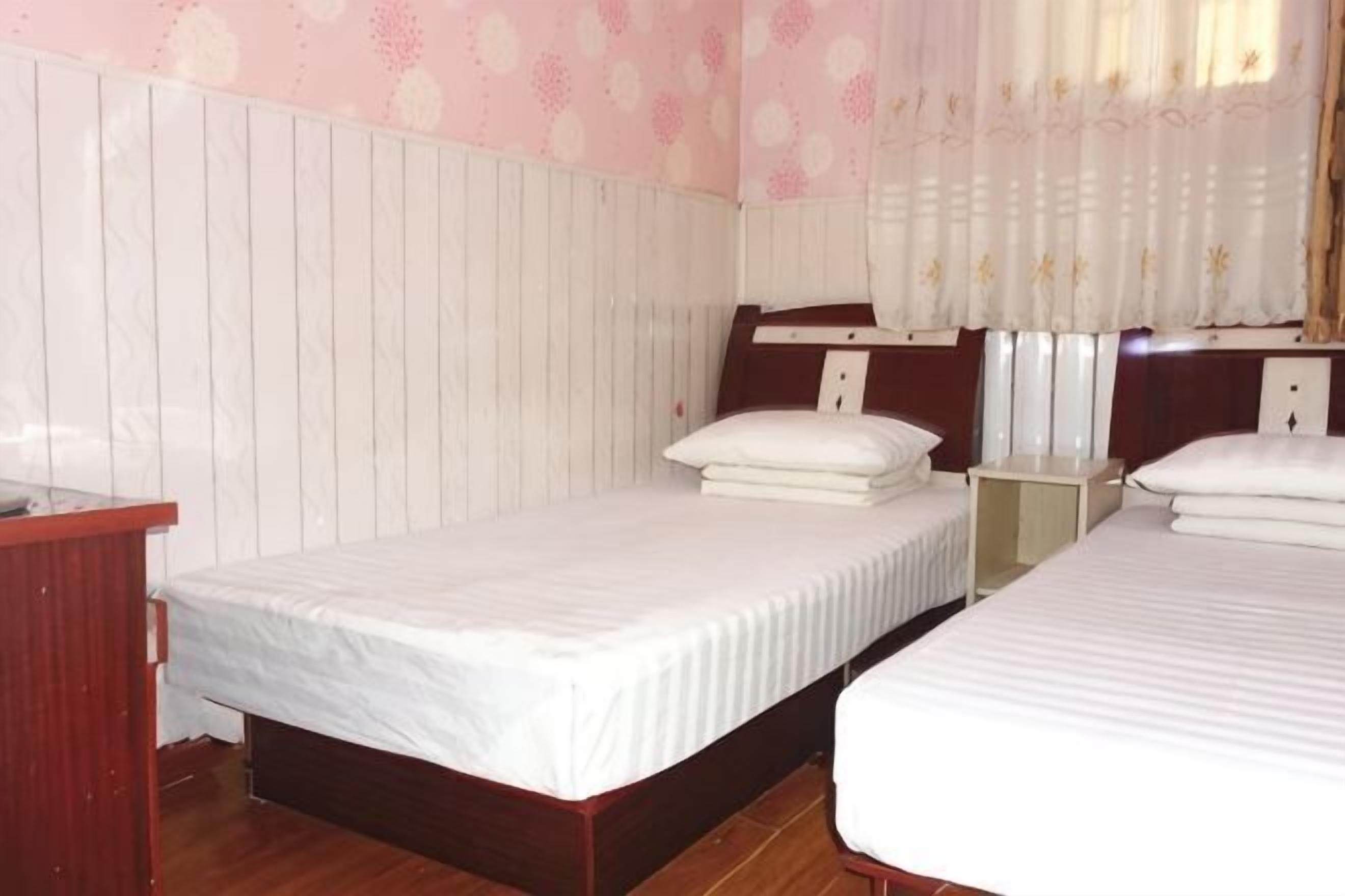 Ein Zimmer mit zwei Einzelbetten, einem Holztisch, einem kleinen Tischchen und einem Kleiderschrank.