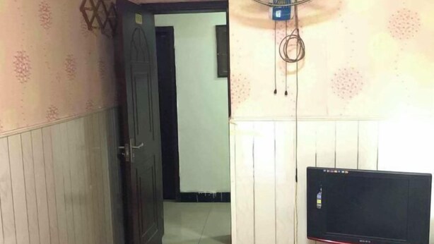 A room with a wooden door, a wall-mounted fan, and a computer monitor. - Shun Feng Yuan Hostel (Qingdao)
