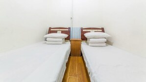 A small, clean room with two single beds, a wooden nightstand, and a striped towel hanging between the beds. - Shun Feng Yuan Hostel (Qingdao)