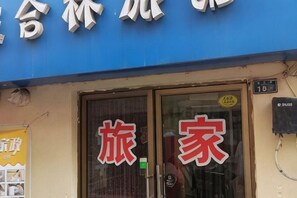 A storefront with large red Chinese characters, a glass door, and a blue awning. - Shun Feng Yuan Hostel (Qingdao)
