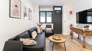 A modern living room with a black leather sofa, a wooden coffee table, and a television on a wooden stand. - "Las Damas de Madrid 10 minutes from downtown" (Madrid)