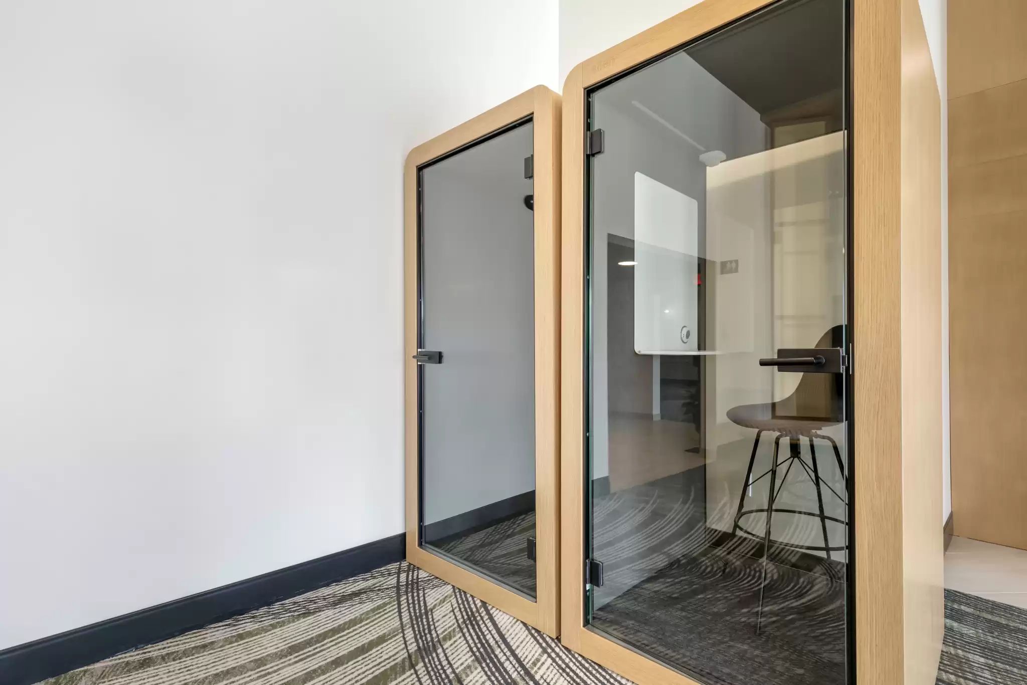 Ein moderner Büroarbeitsplatz mit Glastüren, Holzboden und einem Stuhl im Hintergrund.