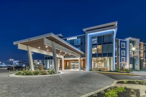 Un hôtel moderne, reconnaissable à son grand panneau « CAMBRIA », à son entrée abritée et à sa façade bien éclairée.