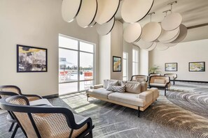 A modern lounge area with a sofa, chairs, and artwork on the walls. - Cambria Hotel Rehoboth Beach (Rehoboth Beach)