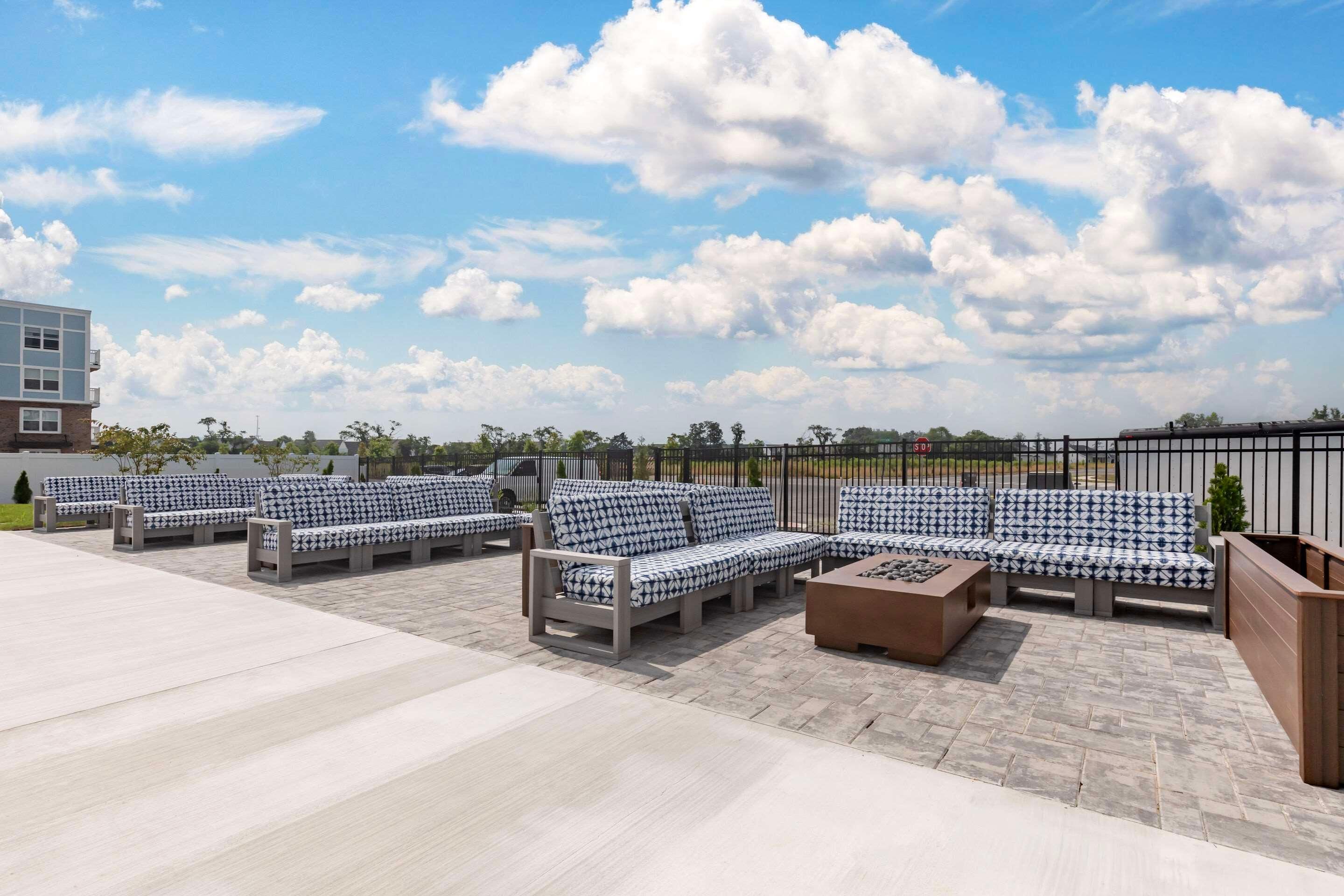 Een terras met meerdere banken en een salontafel, een houten plantenbak en een betegelde vloer.