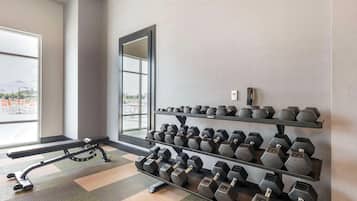 A gym with a bench, dumbbells, and a large window.