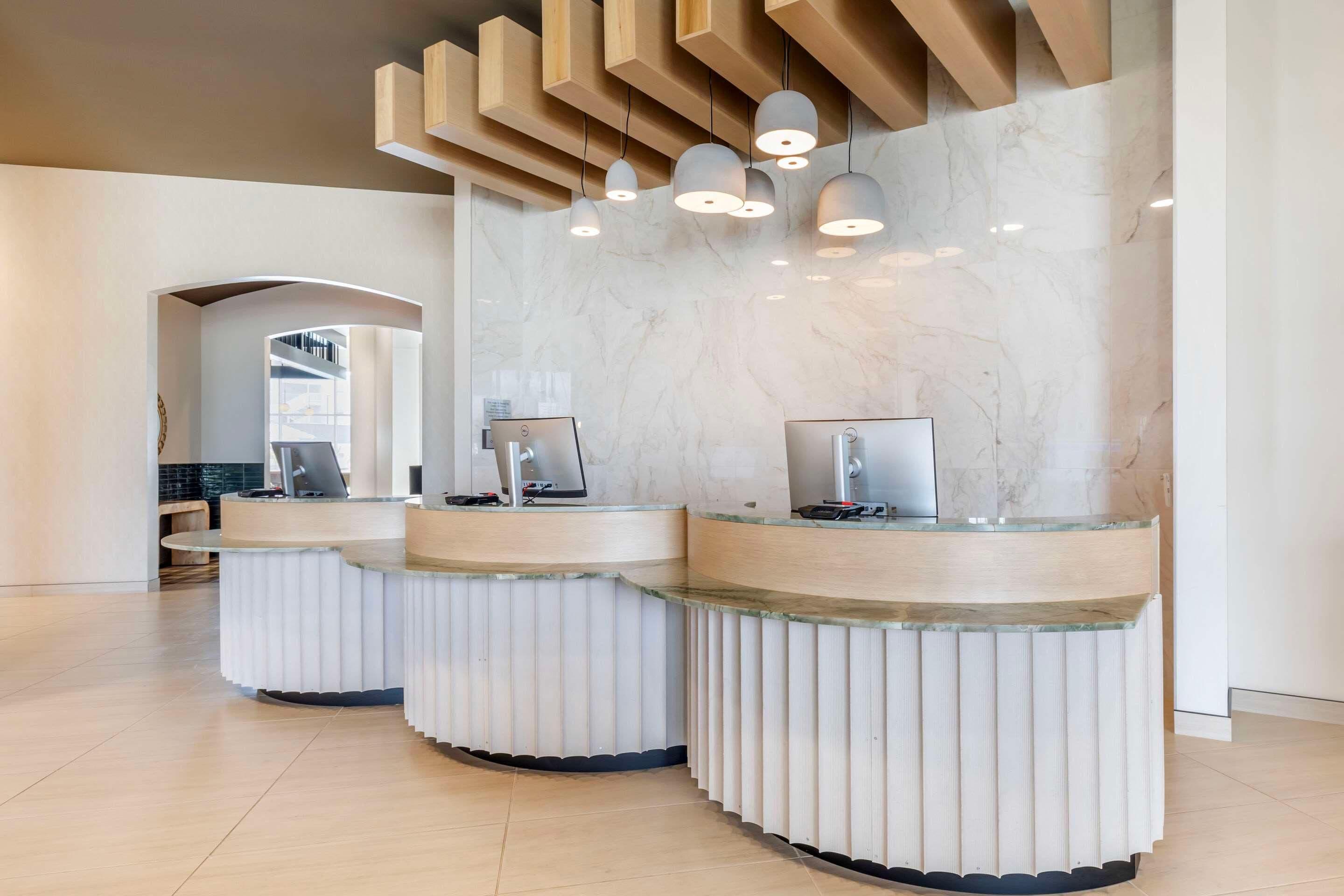 A reception area with three curved counters, marble walls, and pendant lighting.