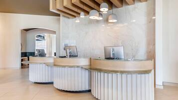 A reception area with three curved counters, marble walls, and pendant lighting.