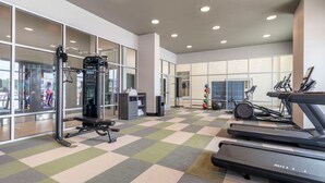 Ein Fitnessraum mit Laufbändern, Krafttrainingsgeräten und einer Spiegelwand.