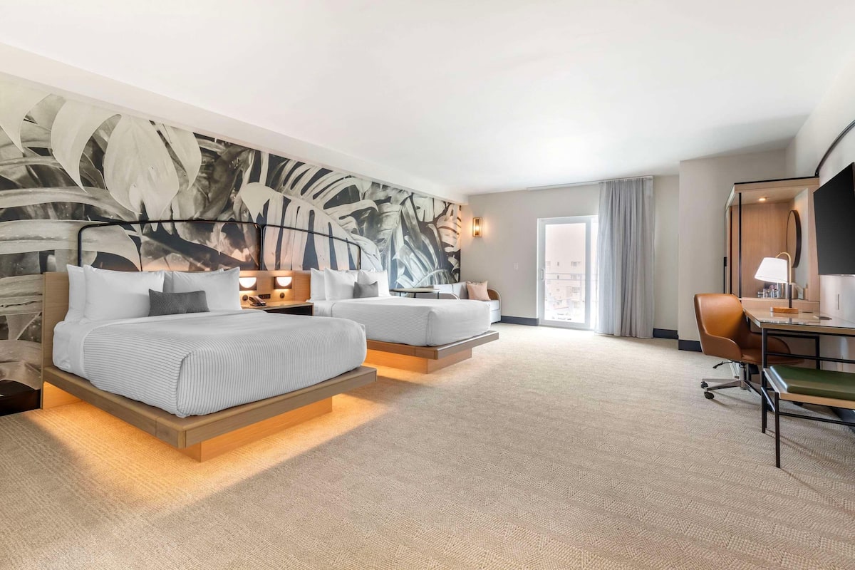 A hotel room with a large bed, a desk, and a chair.