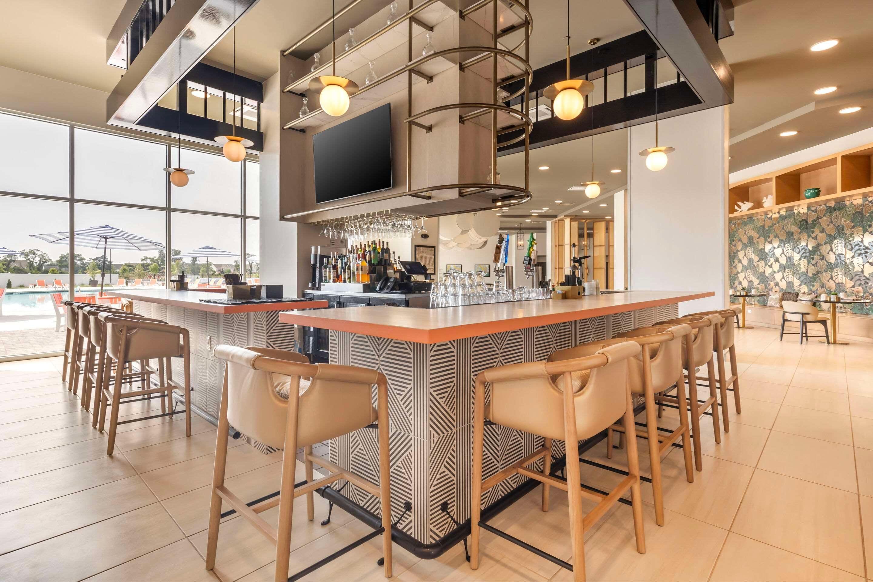 A modern bar area with a patterned bar counter, multiple bar stools, and a large window offering a view of the outdoors.