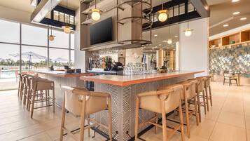 A modern bar area with a patterned bar counter, multiple bar stools, and a large window offering a view of the outdoors.