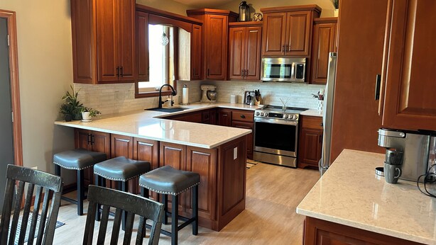 A kitchen with wooden cabinets, a stainless steel stove, a microwave, and a sink. - Entertainer's Dream - Quick drive to Lambeau - Hot Tub, Bar, & 85" TV. (Green Bay)