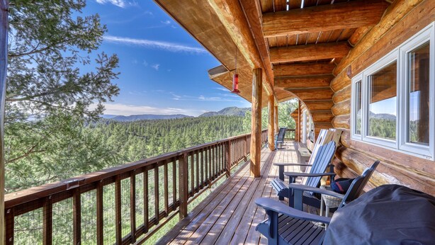 A wooden deck with a view of a forest and mountains. - Scenic 4BR Log Cabin w/ MTN views (Pagosa Springs)