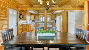 A wooden cabin interior with a dining table, chairs, a chandelier, and a kitchen area. - Scenic 4BR Log Cabin w/ MTN views (Pagosa Springs)