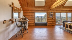 A log cabin interior with a dining area, large windows, and a view of the mountains. - Scenic 4BR Log Cabin w/ MTN views (Pagosa Springs)