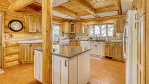 A spacious kitchen with wooden cabinets, a granite countertop, and a clock on the wall. - Scenic 4BR Log Cabin w/ MTN views (Pagosa Springs)