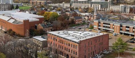 An aerial view of a town with various buildings, including a large brick building with a flat roof and multiple air conditioning units.