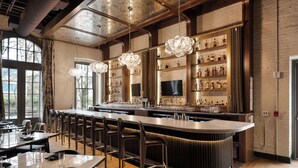 A bar area with a long counter, multiple stools, and a wine display. - The Delegate (Frankfort)