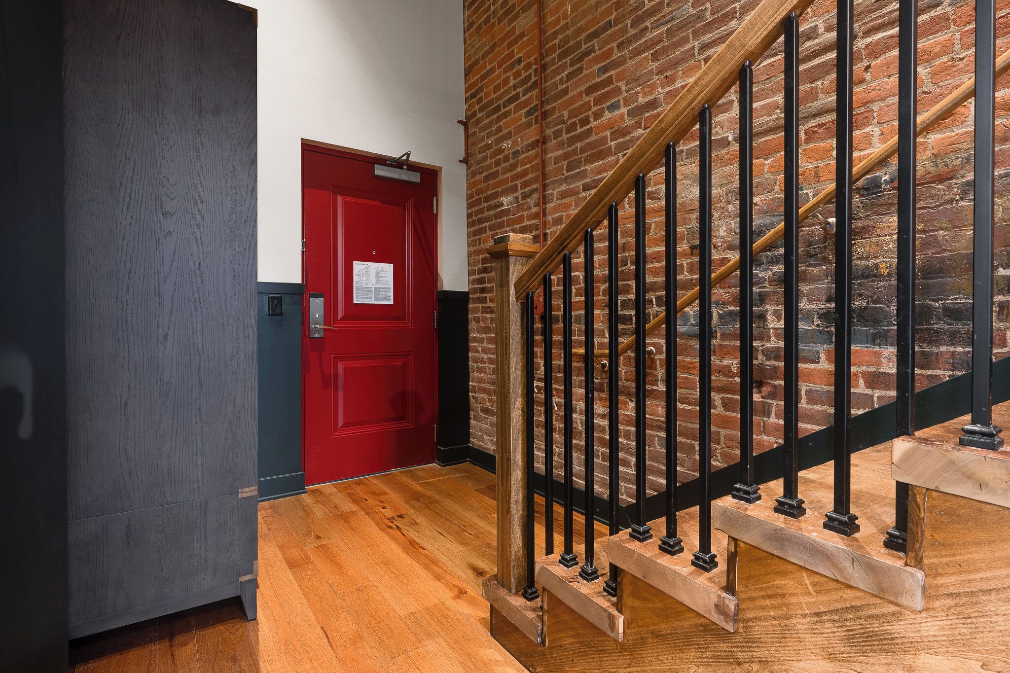 A staircase with wooden steps and black metal railings against a brick wall.