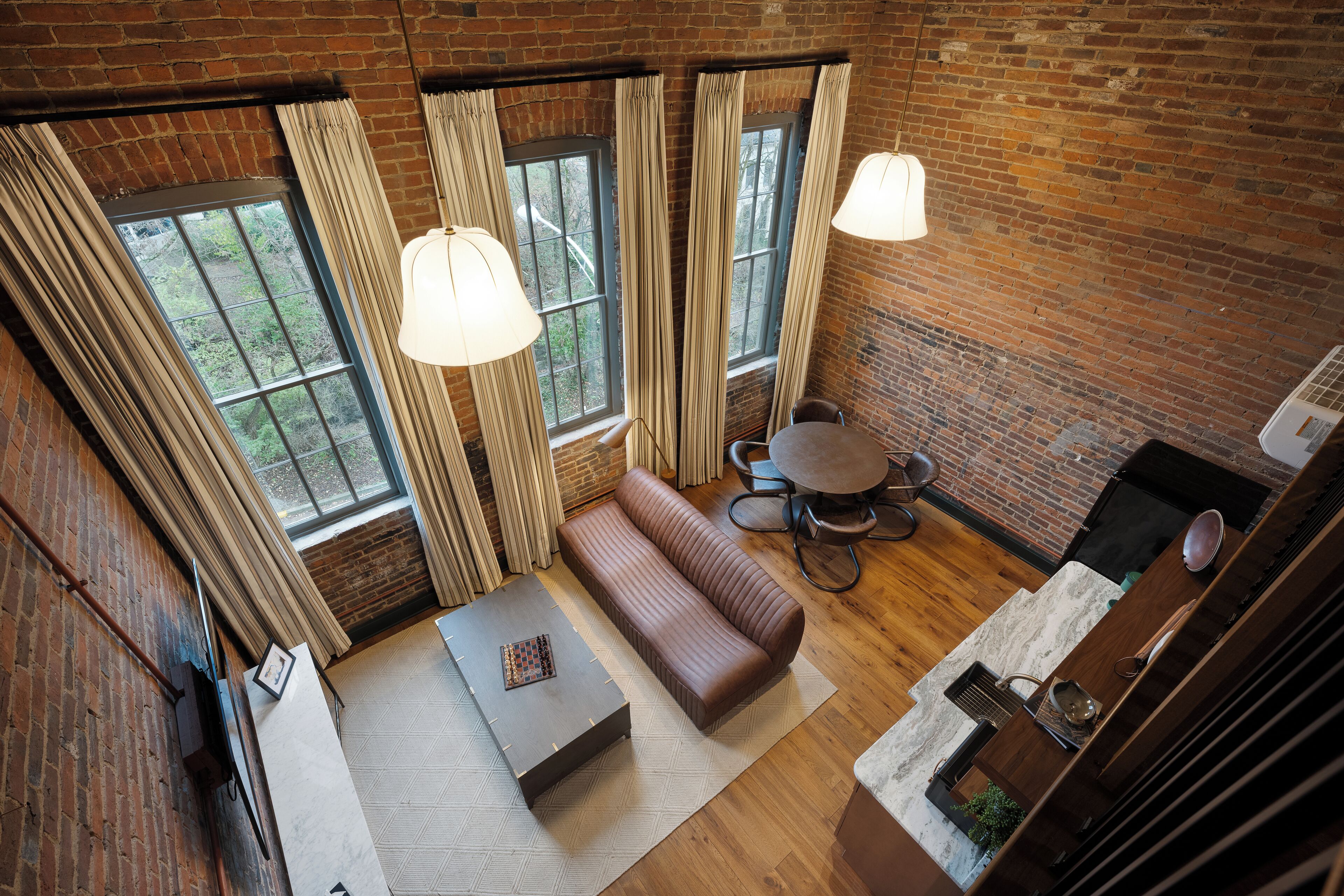A loft-style room with a loft bed, a sofa, a dining table, and a kitchen area.