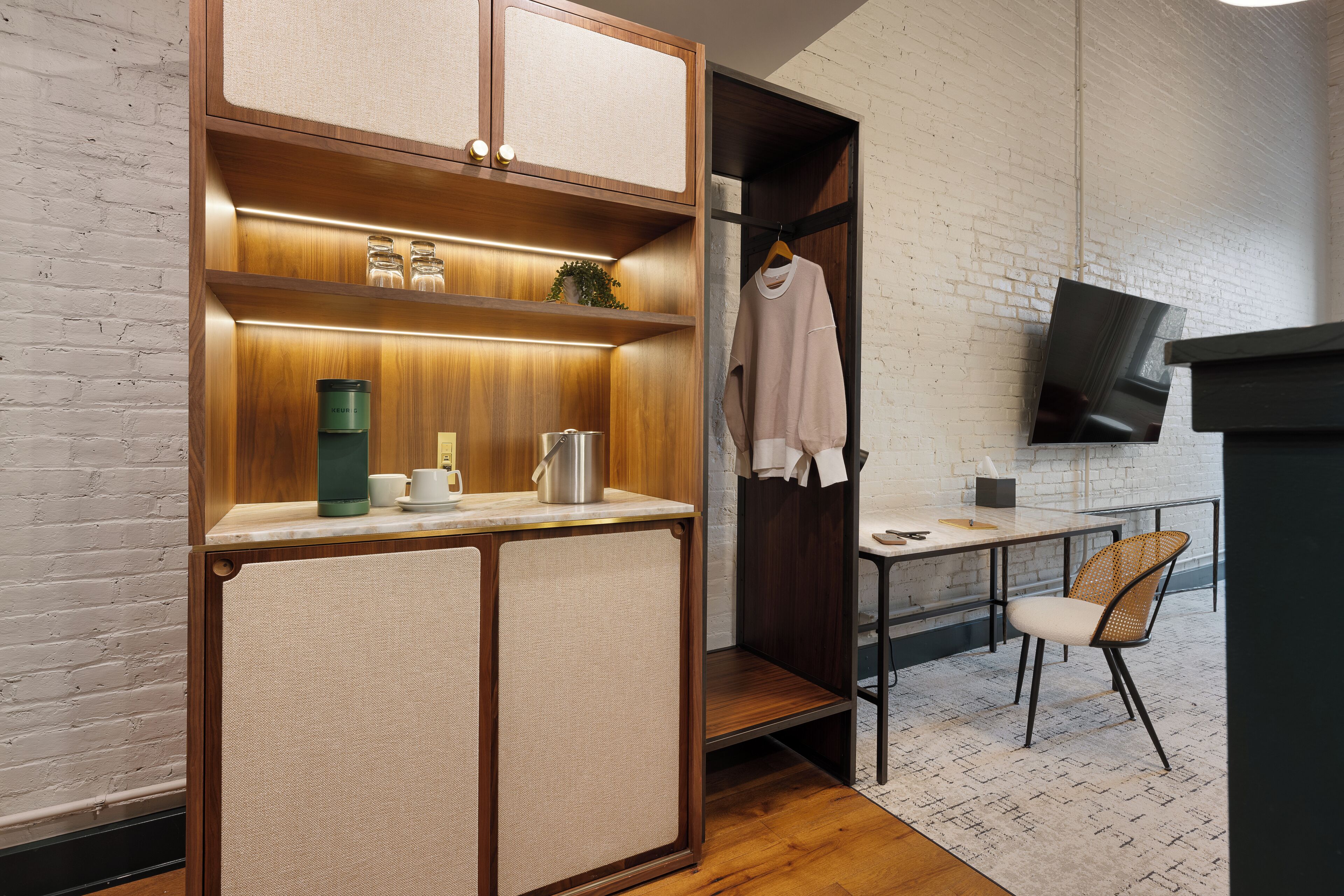 A compact kitchen with wooden cabinetry, a countertop, and a hanging garment.