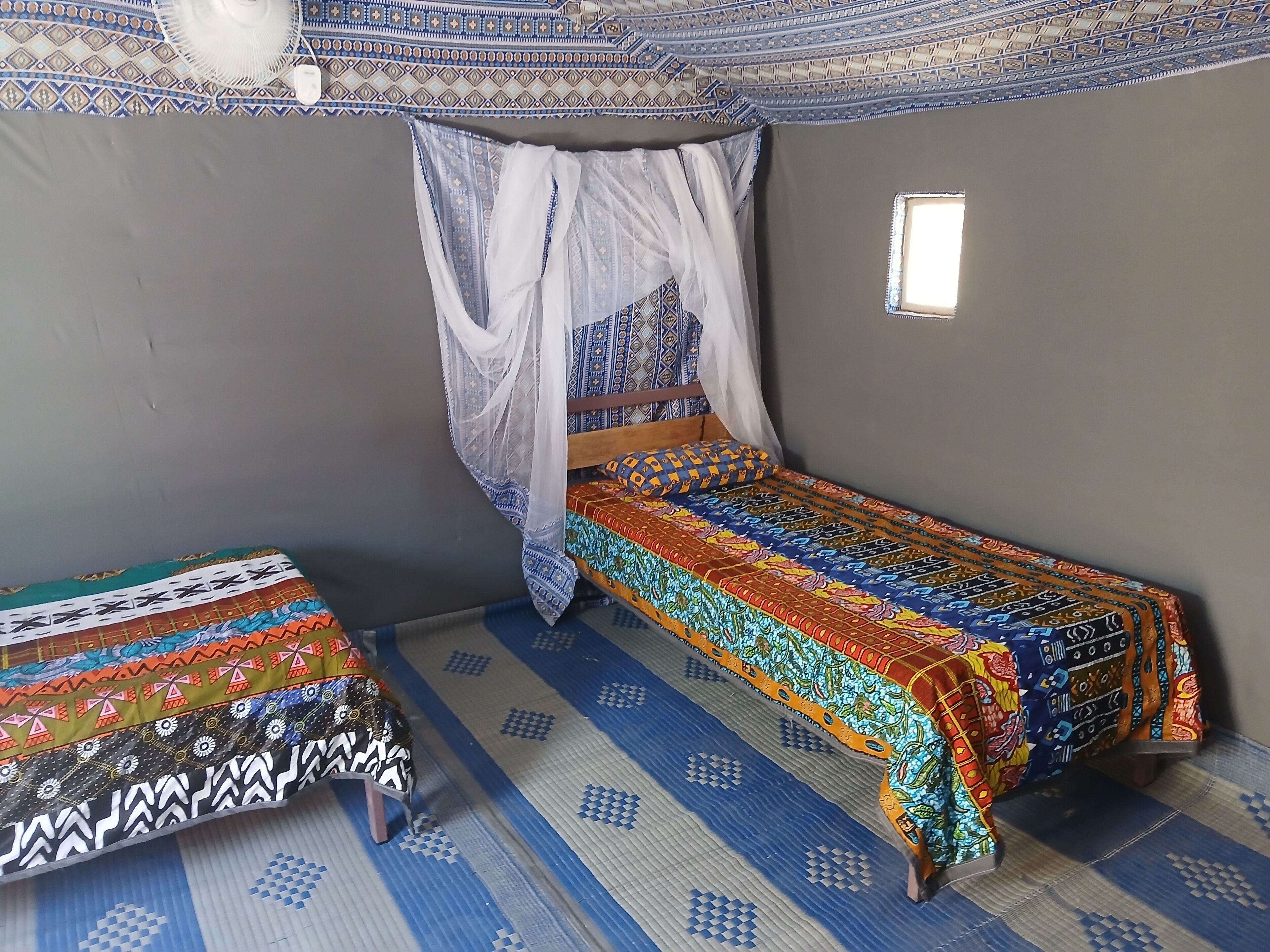 A room with a bed and a small table, both covered with patterned bedspreads.