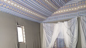 Una cama individual con un edredón de diseño colorido, cabecera de madera y dosel blanco.