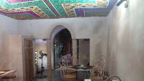 Un comedor con una mesa y sillas, un ventilador y un arco que da a otra habitación.