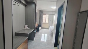 A modern hotel room with a bed, a desk, a chair, and a window.