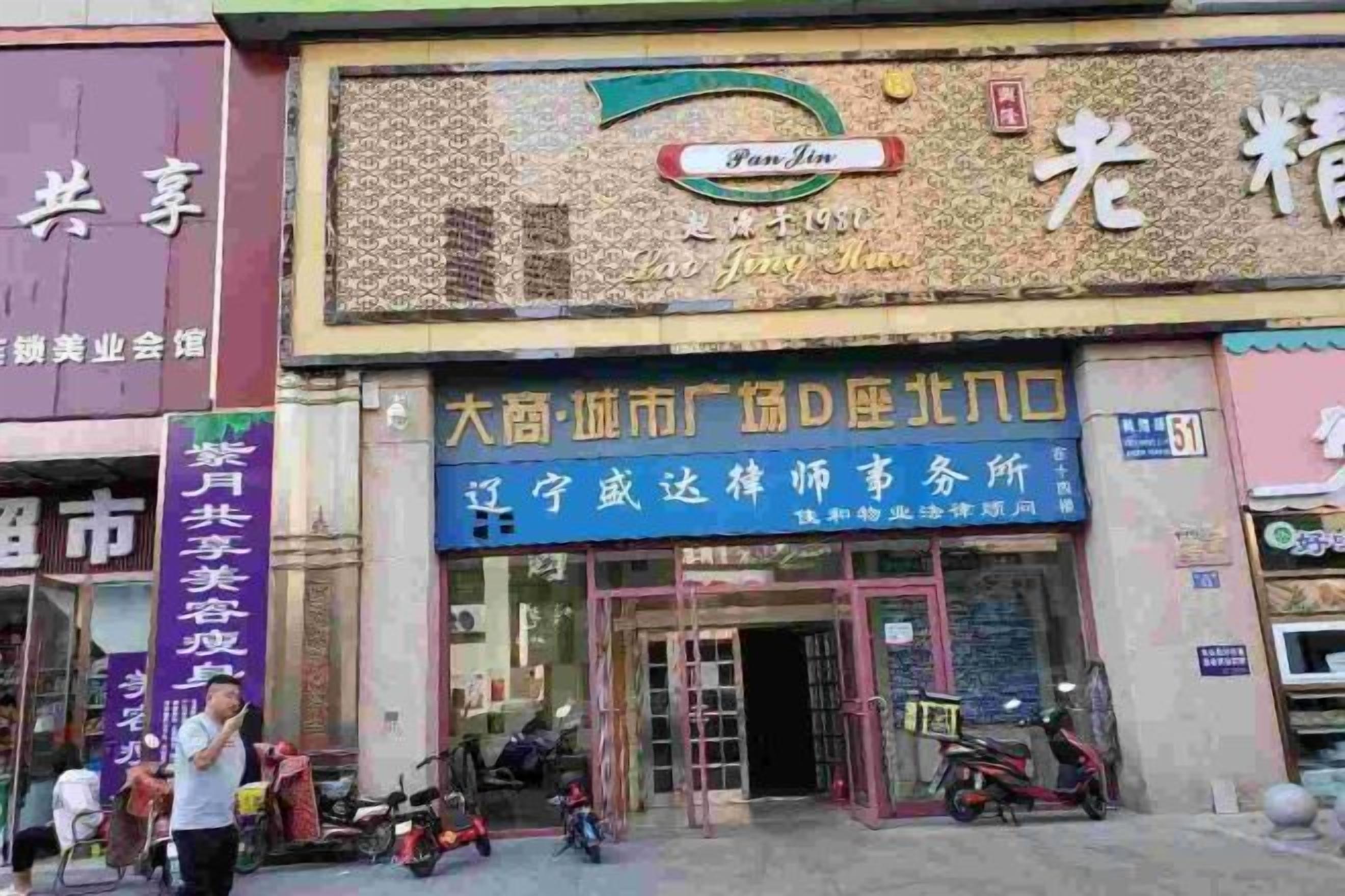 A building with a sign for a business establishment. There are people and a motorcycle outside.