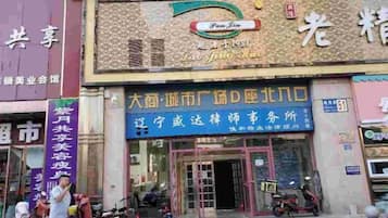 A building with a sign for a business establishment. There are people and a motorcycle outside.