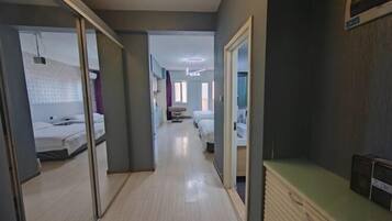Un pasillo de hotel con suelo de madera, un armario espejado y una encimera verde.