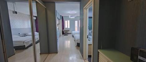 A hotel corridor with a wooden floor, a mirrored wardrobe, and a green counter.