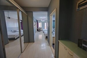 Un couloir d’hôtel avec un plancher en bois, une armoire à miroir et un comptoir vert.