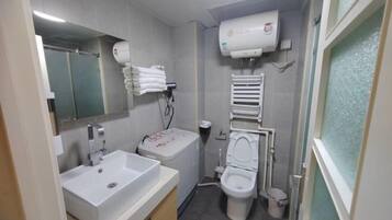 Un baño con lavamanos, inodoro y secamanos.