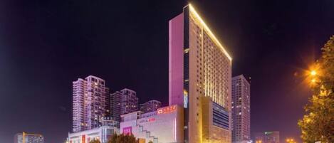 A high-rise building with multiple floors, illuminated by artificial lighting, and surrounded by other tall structures.