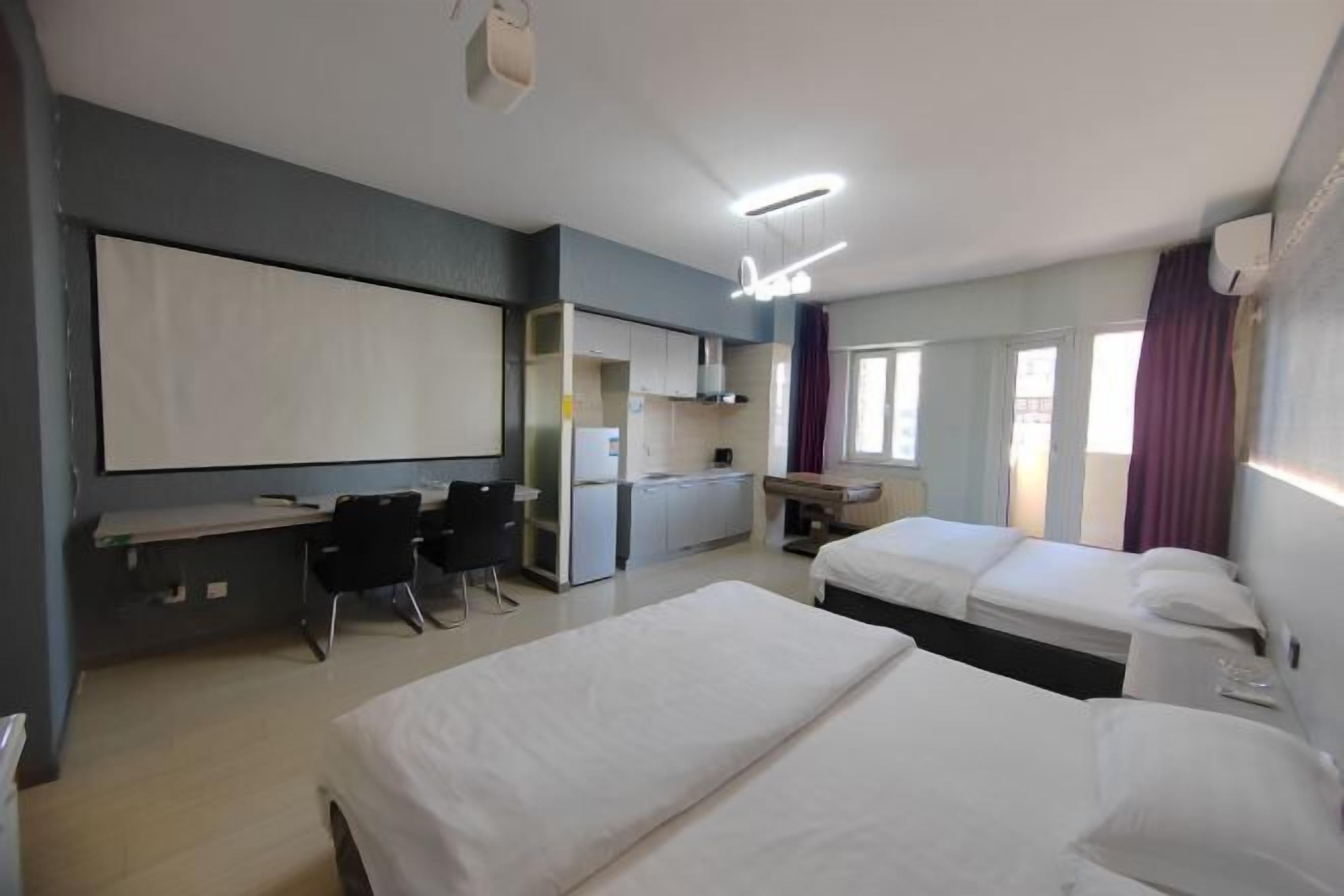 Habitación de hotel con dos camas, un escritorio, una silla, un televisor y una ventana con cortinas.