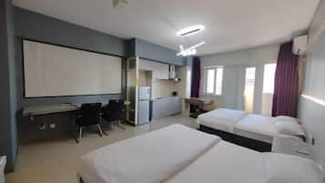 Habitación de hotel con dos camas, un escritorio, una silla, un televisor y una ventana con cortinas.