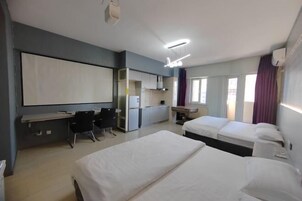 Habitación de hotel con dos camas, un escritorio, una silla, un televisor y una ventana con cortinas.