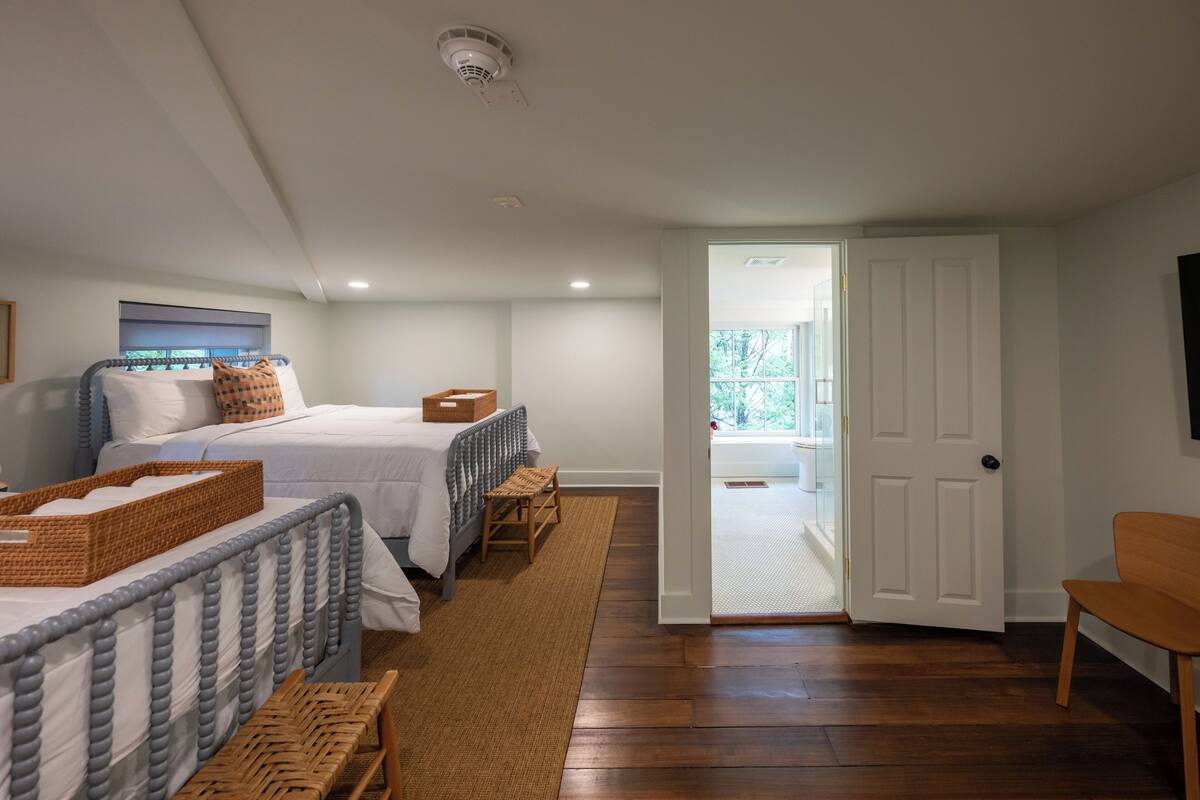 A bedroom with two beds, a wooden chair, and a basket on the floor.