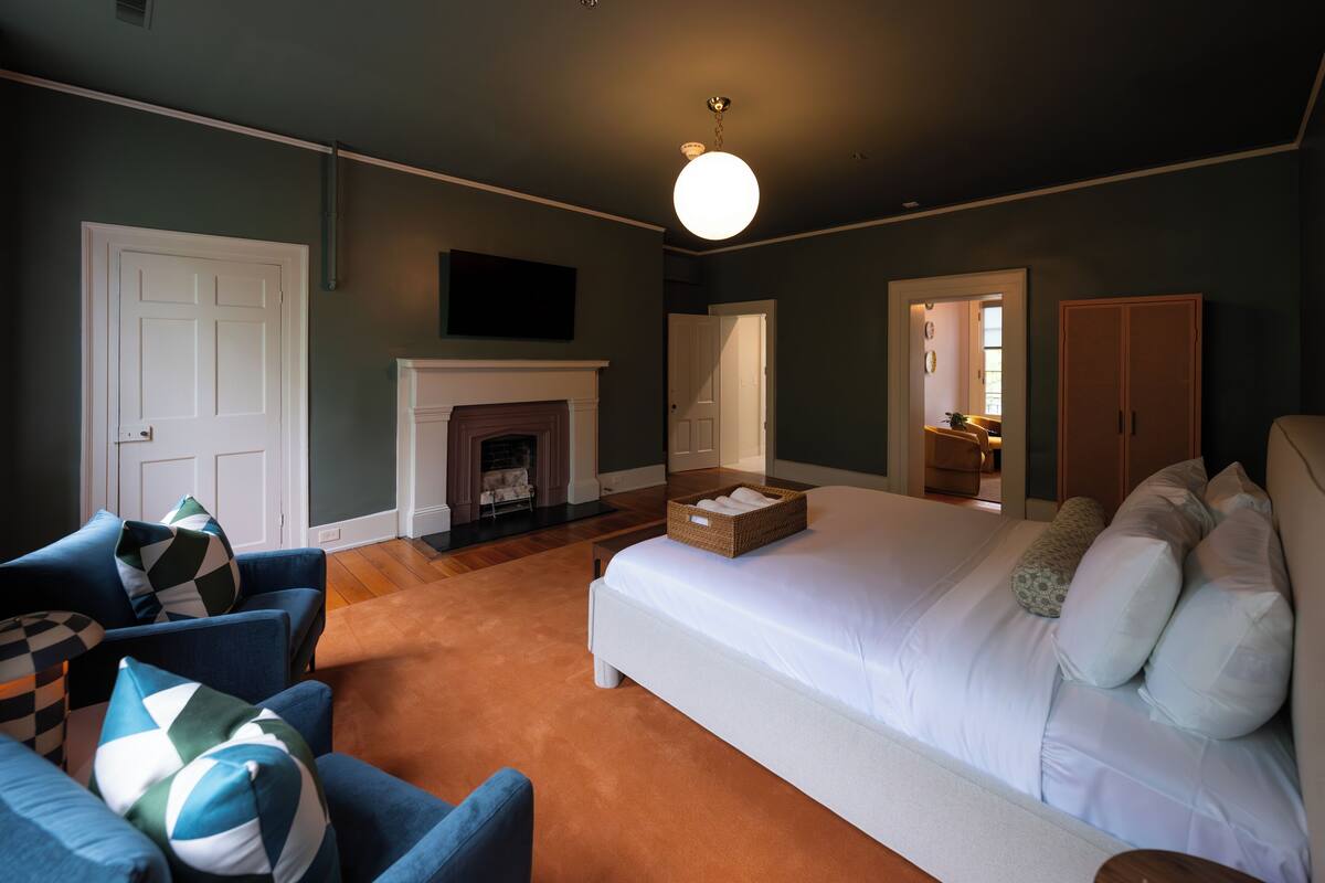 A bedroom with a large bed, a fireplace, a sofa, and a wardrobe.
