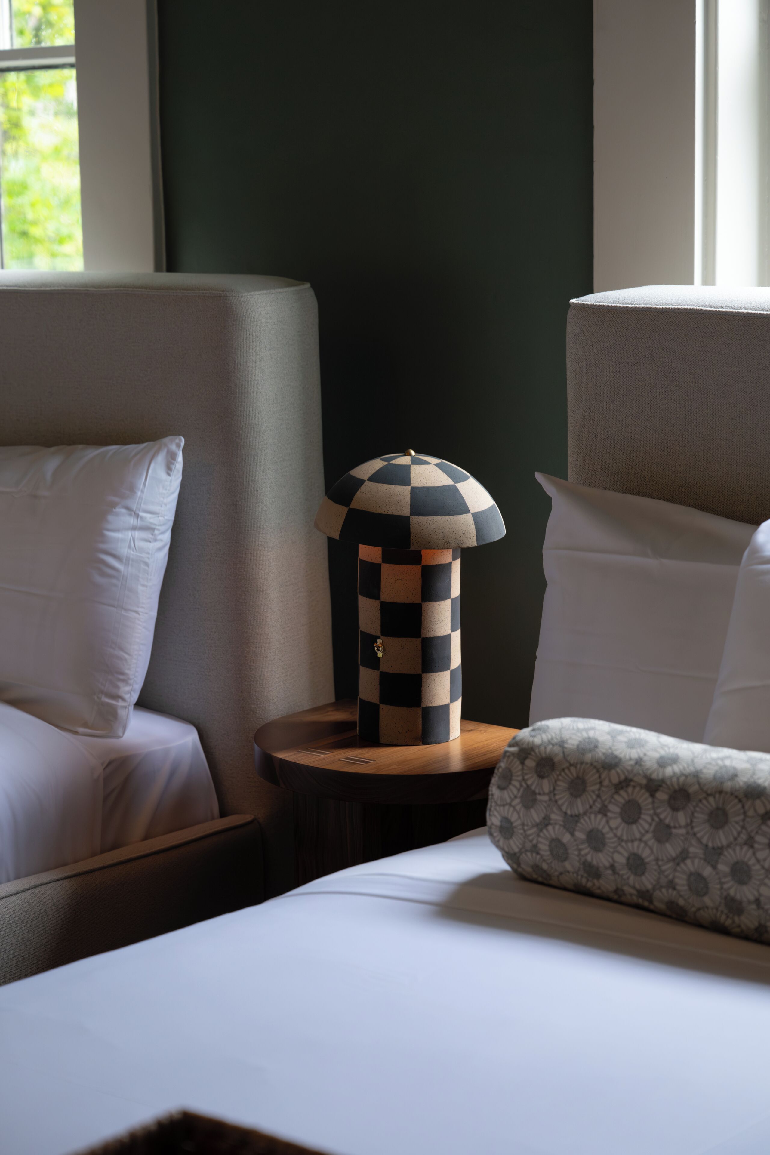Habitación de hotel con cama, dos sillones, una mesita de noche con lámpara y vistas al exterior.