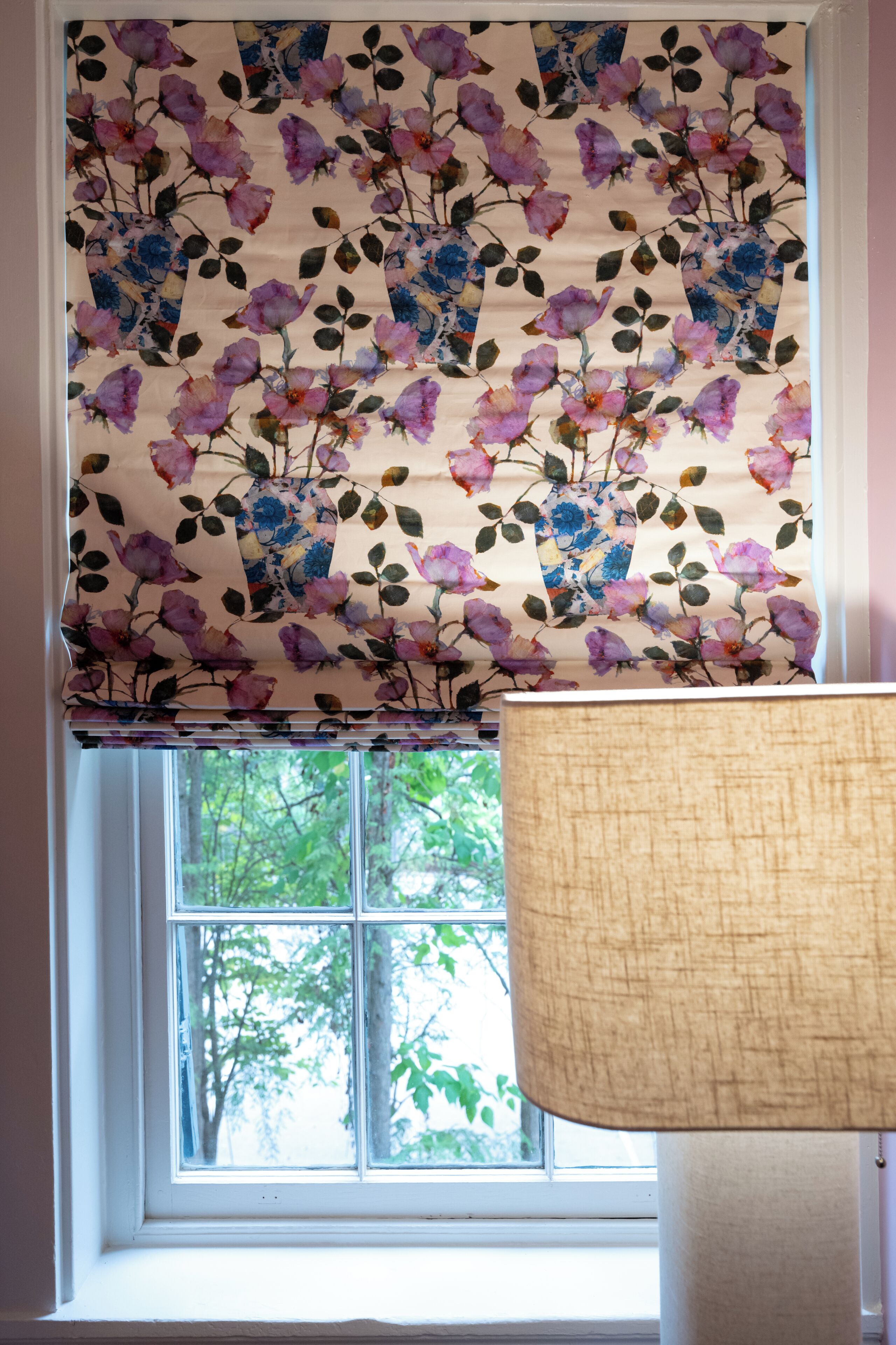 A window with a floral valance and a lamp.