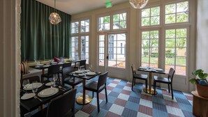A dining area with tables set for two, large windows, and a checkered floor pattern. - The Ashbrook Hotel (Frankfort)