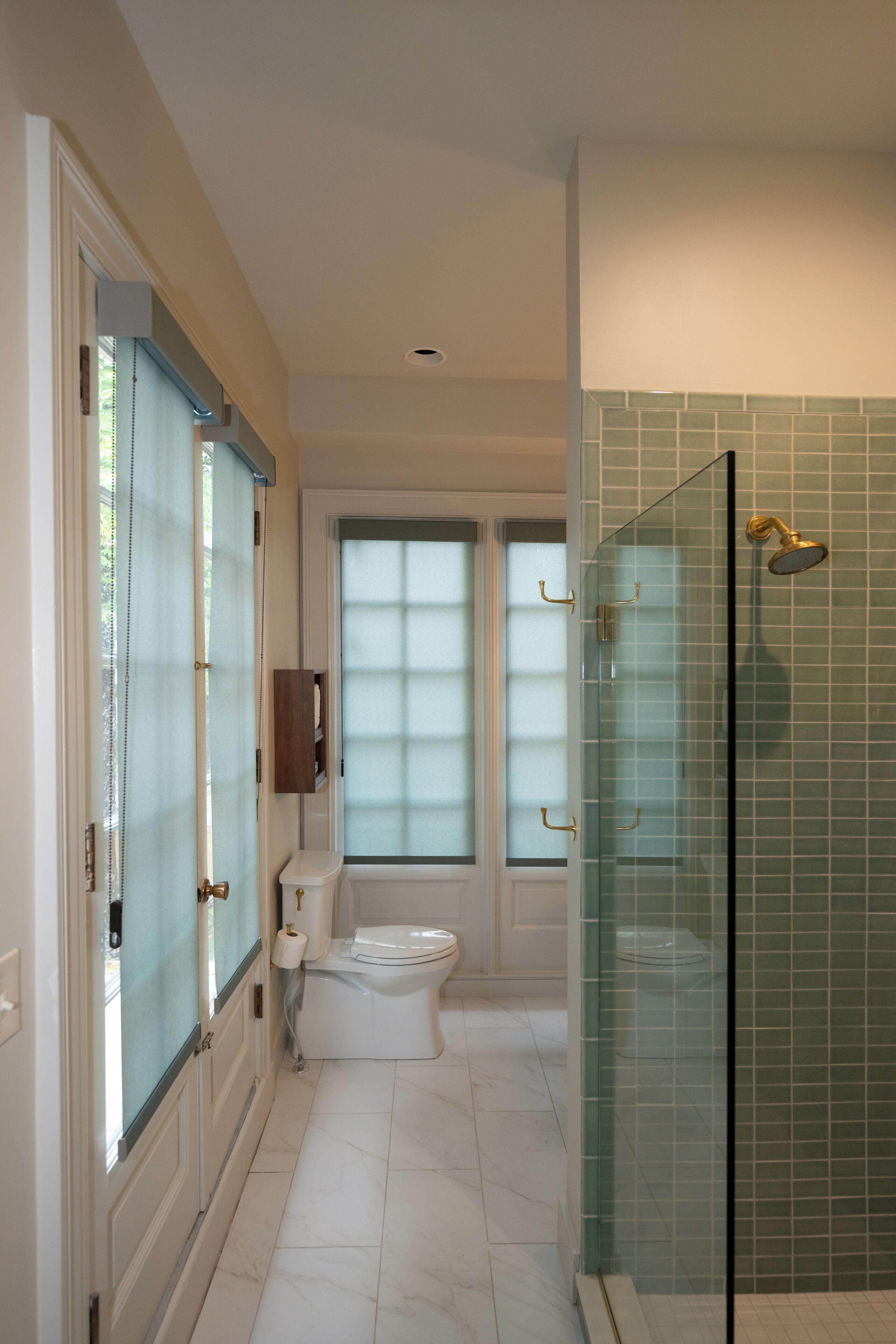 Un bagno con il water, cabina doccia in vetro e porte in vetro satinato.