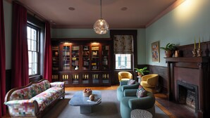 A cozy living room with a sofa, armchairs, a coffee table, and a fireplace. - The Ashbrook Hotel (Frankfort)