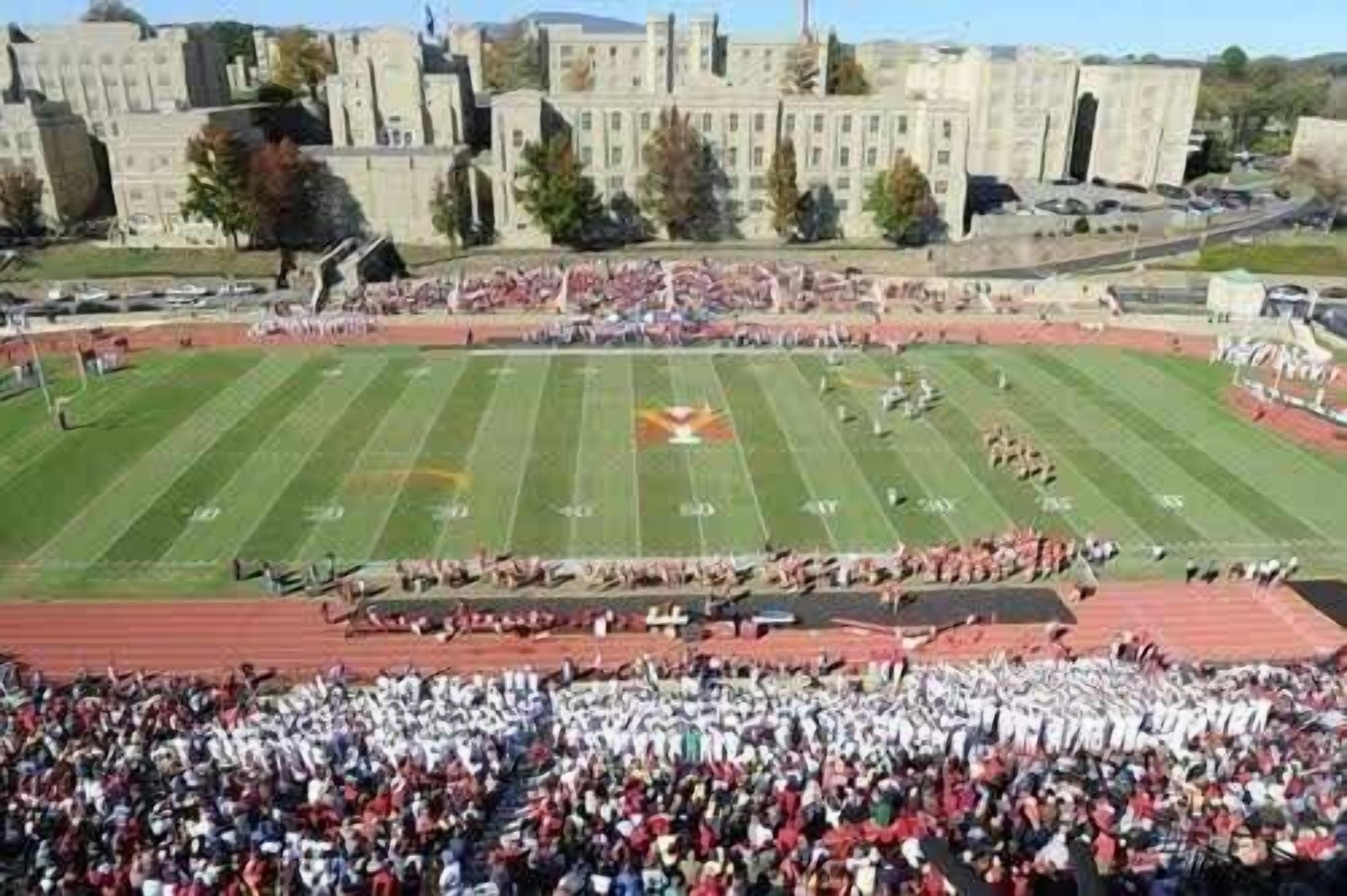 A stadium with a football field, bleachers, and a crowd of spectators.