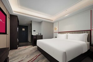 A modern hotel room with a large bed, a bedside table with a lamp, and a view of the hallway. - Mövenpick By Accor Binjiang Nanjing (Nanjing)