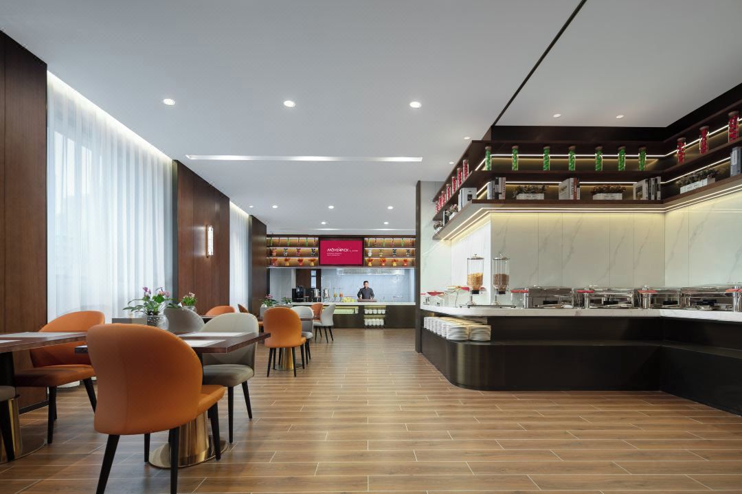 A modern restaurant with a long counter, multiple seating areas, and a visible kitchen area.
